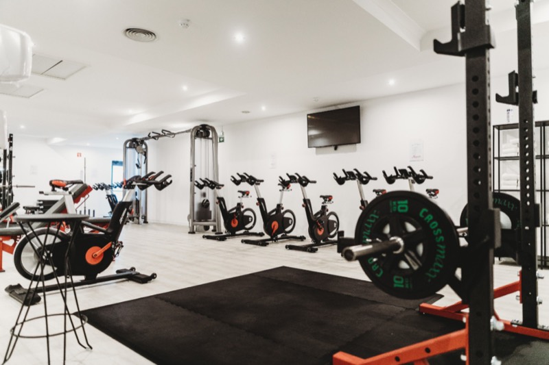 A gym floor with spin bikes and weight equipment