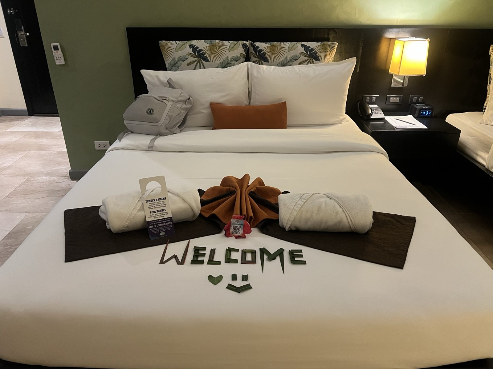 A neatly made hotel room bed with folded towels